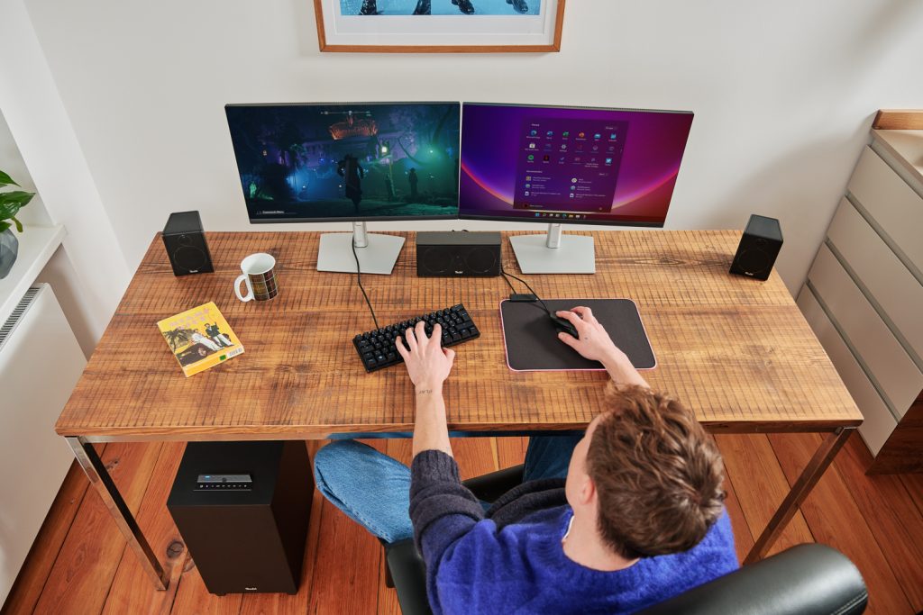 Man op gaming-pc met surround speakers.